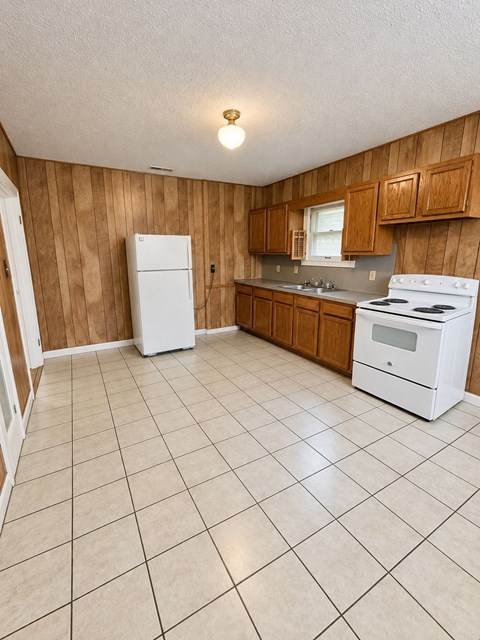 A kitchen with white appliances and wooden cabinets.