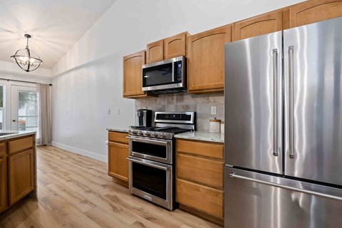 A kitchen with wooden cabinets and a stainless steel refrigerator.