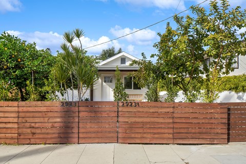 A house with a brown fence and trees in front.