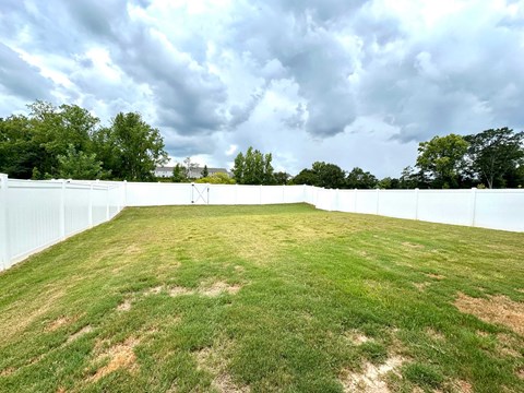 A large white fence encloses a grassy field.