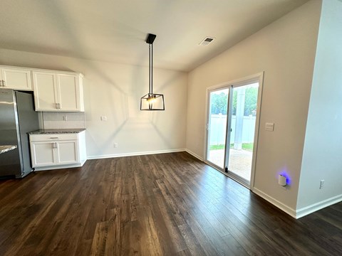 A kitchen with white cabinets and a wooden floor.