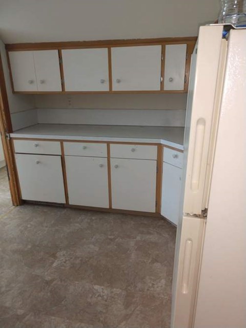A kitchen with white cabinets and a white refrigerator.