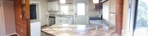 A kitchen with a marble counter top and white cabinets.