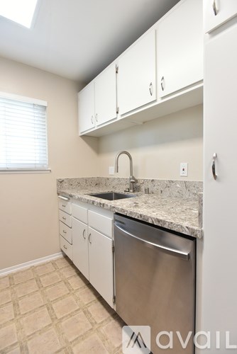 A kitchen with a sink, dishwasher, and cabinets.