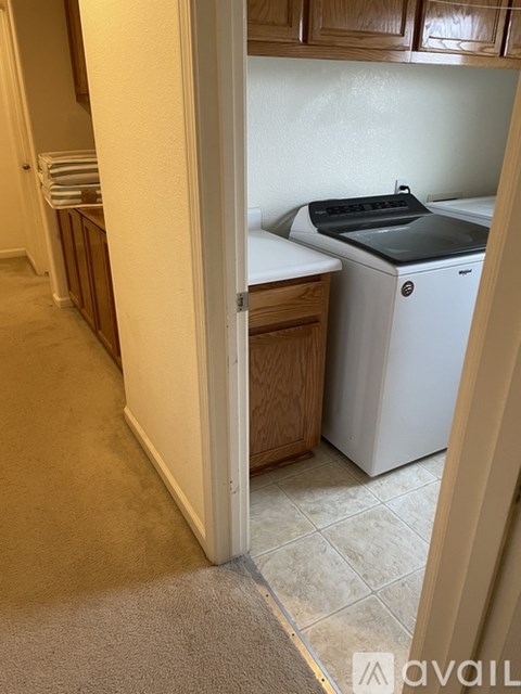 A white dishwasher is in a kitchen next to a white wall.