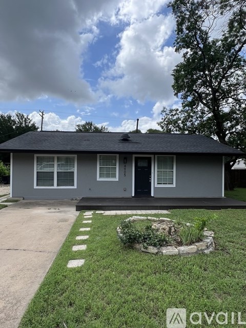 A house with a grey roof and a front yard with a small garden.