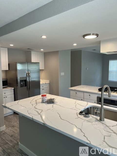 A kitchen with a marble countertop and stainless steel appliances.