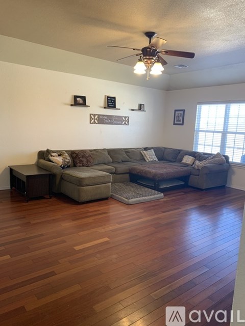 A living room with a grey couch and a wooden floor.