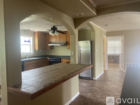 A kitchen with a wooden countertop and a ceiling fan.
