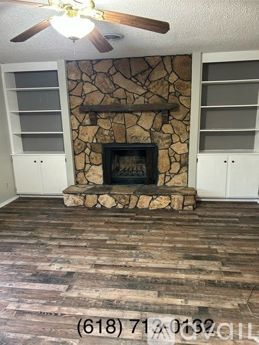 A room with a stone fireplace and wood flooring.