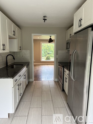 A kitchen with white cabinets and a black counter top.