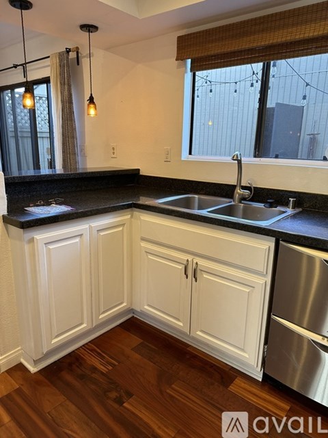 A kitchen with white cabinets and a black countertop.