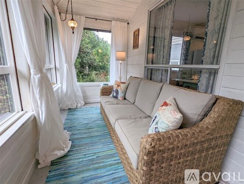 A living room with a couch and a window with curtains.