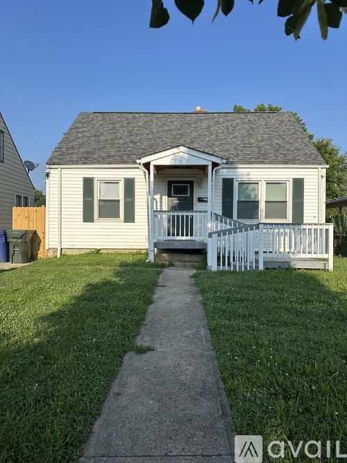 A small house with a grey roof and a white picket fence.