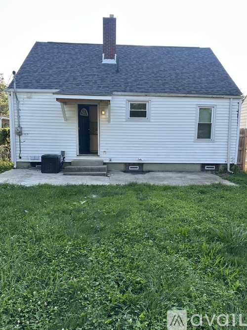 A small white house with a black door and a brown roof.