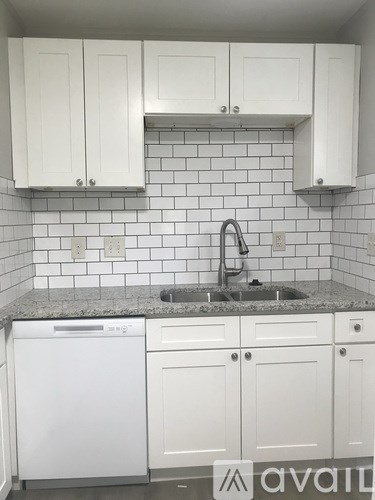 A kitchen with white cabinets and a granite countertop.