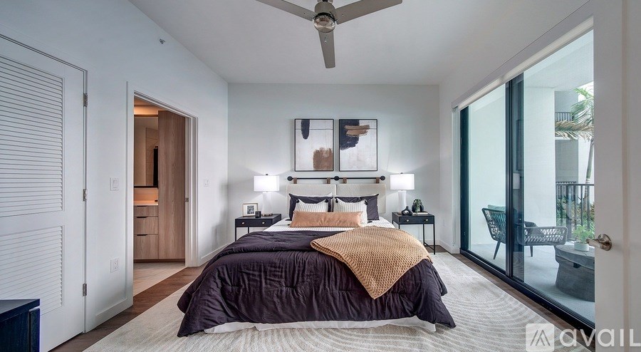 A bedroom with a bed, a ceiling fan, and a sliding glass door.