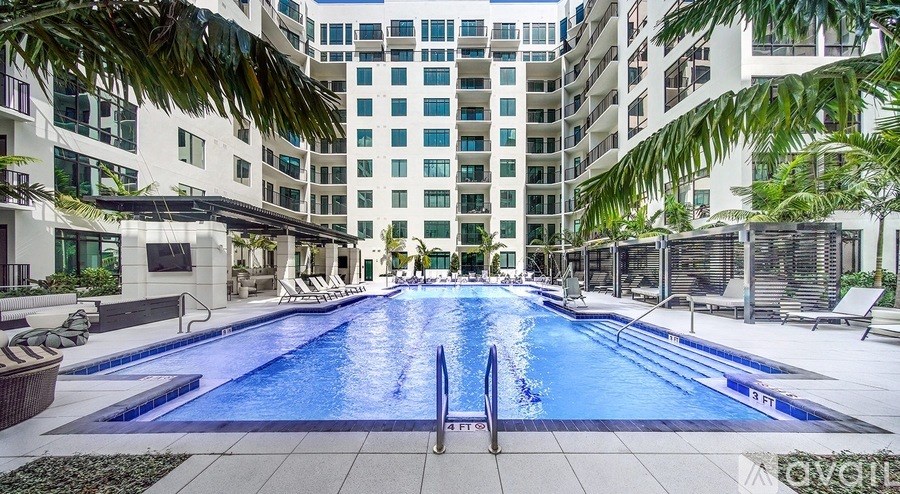 A large indoor swimming pool with lounge chairs and palm trees.
