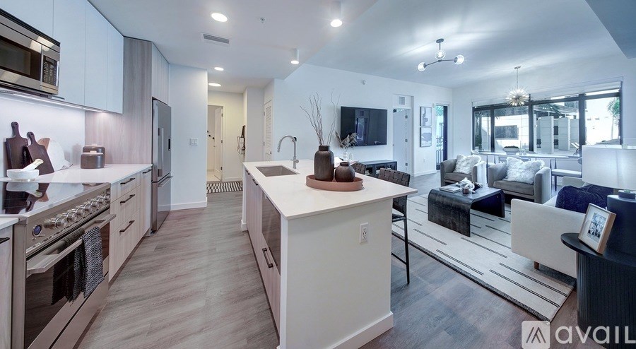 A modern kitchen with a large island and a living area with a couch and a coffee table.