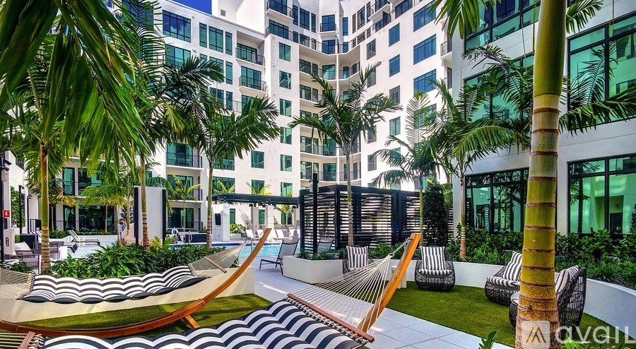 A modern outdoor seating area with a hammock and palm trees.