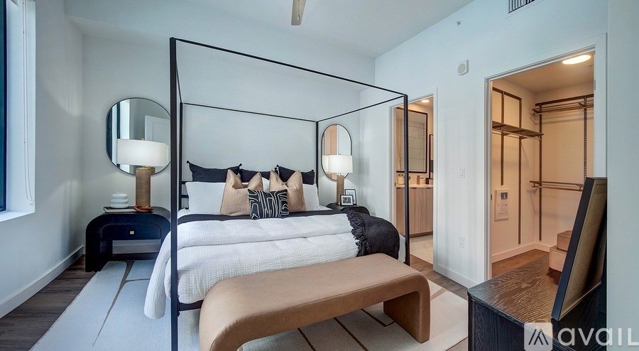 A modern bedroom with a four poster bed and a bench.