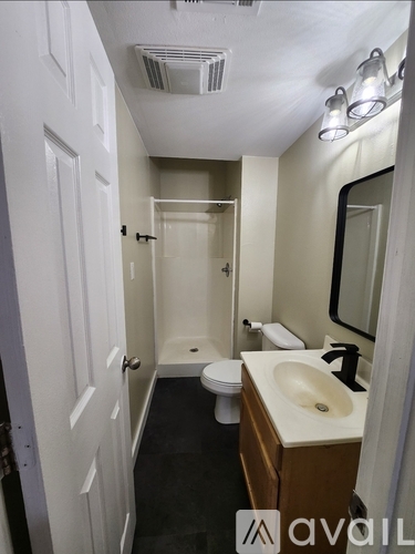 A bathroom with a toilet, sink, and mirror.