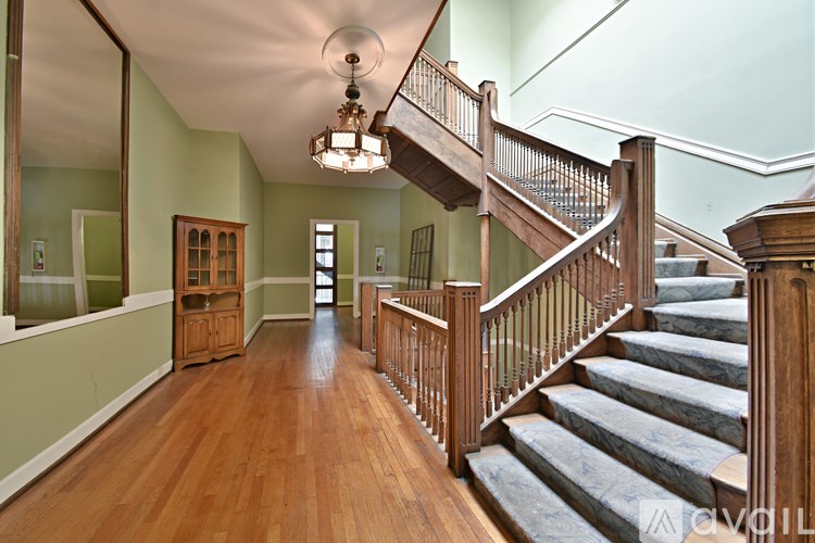 A wooden staircase with a chandelier hanging from the ceiling.