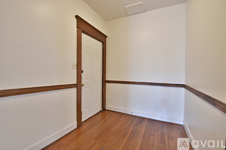 A room with a wooden door and white walls.