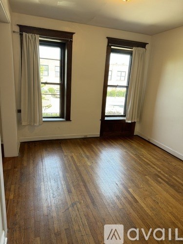 A room with wooden floors and two windows.