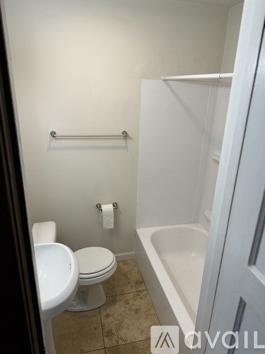 A white toilet sits next to a white sink in a small bathroom.