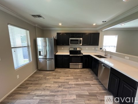 A kitchen with black cabinets and a stainless steel refrigerator.