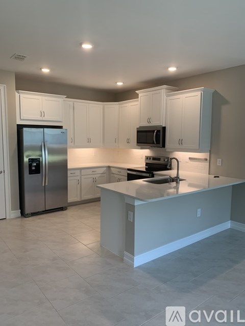 A kitchen with a refrigerator, microwave, and oven.