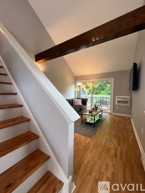 A wooden staircase with white railings leads to a living room with a couch and a coffee table.