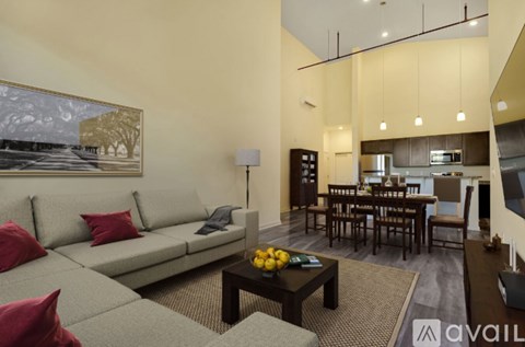 A living room with a grey couch and a painting on the wall.