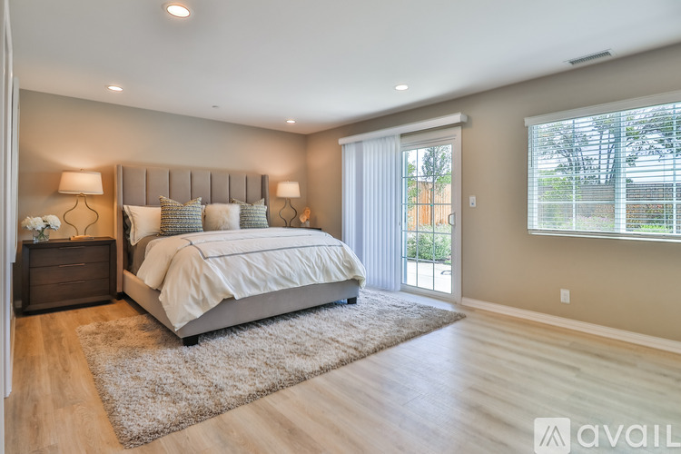 A bedroom with a large bed and a window with blinds.