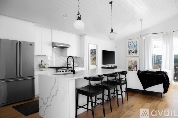 A modern kitchen with a white island and black chairs.
