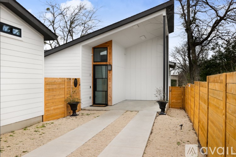 A modern house with a white exterior and a wooden fence.