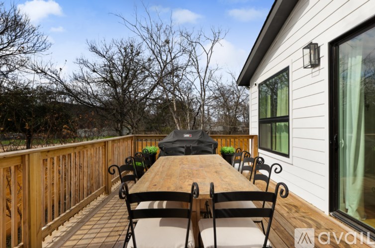 A wooden deck with a table and chairs and a black bag on it.