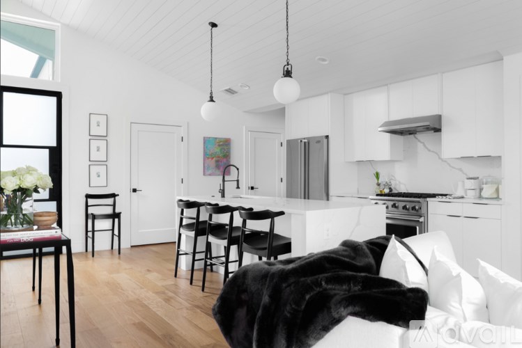 A black dog is sleeping on a white couch in a modern kitchen.