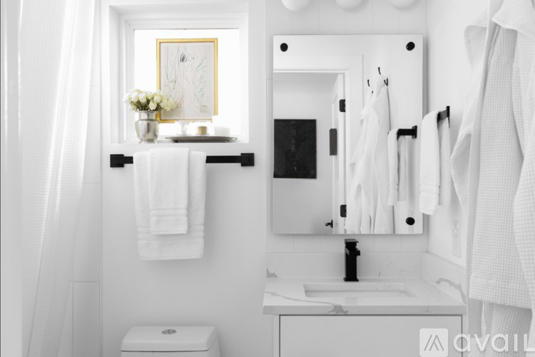 A white bathroom with a toilet, sink, and mirror.