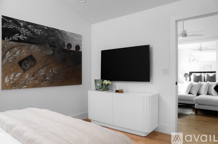 A large painting hangs on the wall above a television in a modern living room.