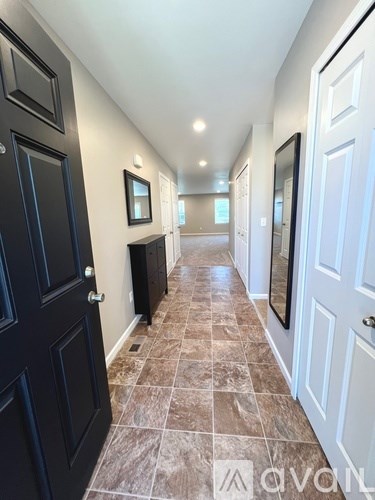 A hallway with tiled floors and white walls.