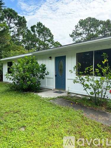 A white house with a blue door and a green lawn.