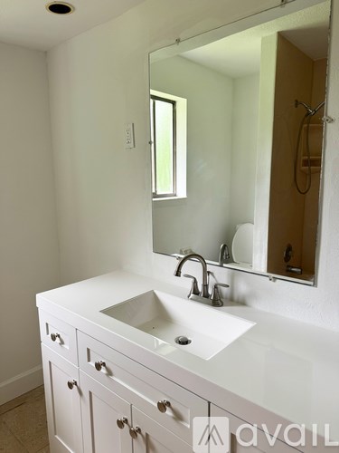 A bathroom with a sink, mirror, and cabinets.
