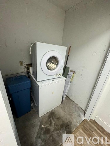 A white washing machine in a small, dirty laundry room.