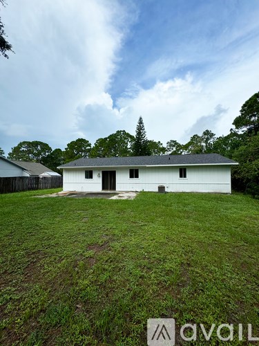 A white house with a grey roof is surrounded by green grass.