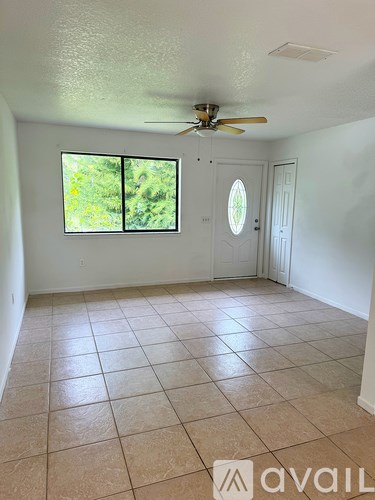 A room with a ceiling fan and a window with a view of greenery outside.