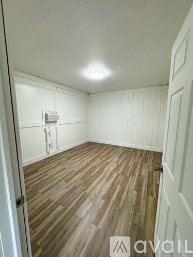 A room with wooden flooring and white walls.