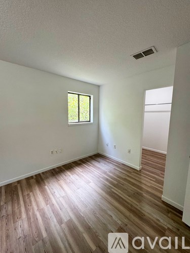 A room with wooden flooring and a window.