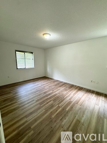 A room with wooden flooring and a window.